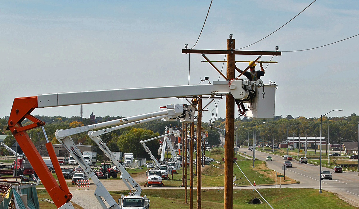 Several utilities linesmen erecting a new line of overhead powerlines.